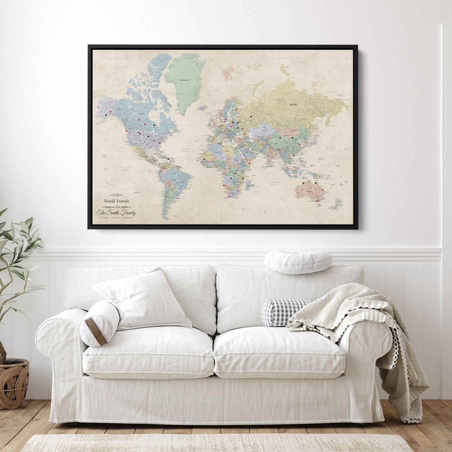 Personalized Sandy Dreams world travel map canvas in a black float frame with red and black push pins hung above white sofa