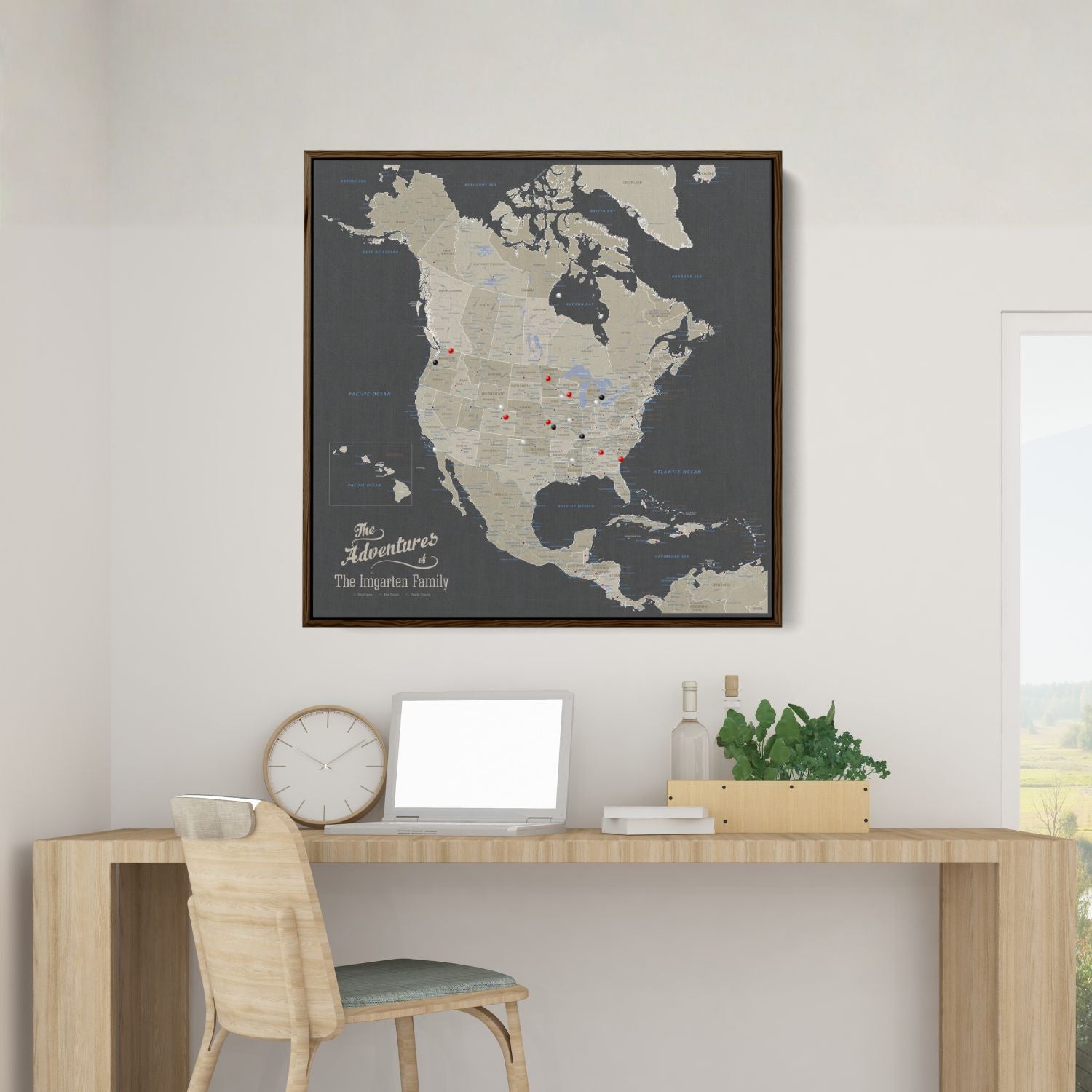 Framed earth toned North America travel map with push pins displayed above a modern wooden desk in a home office setting
