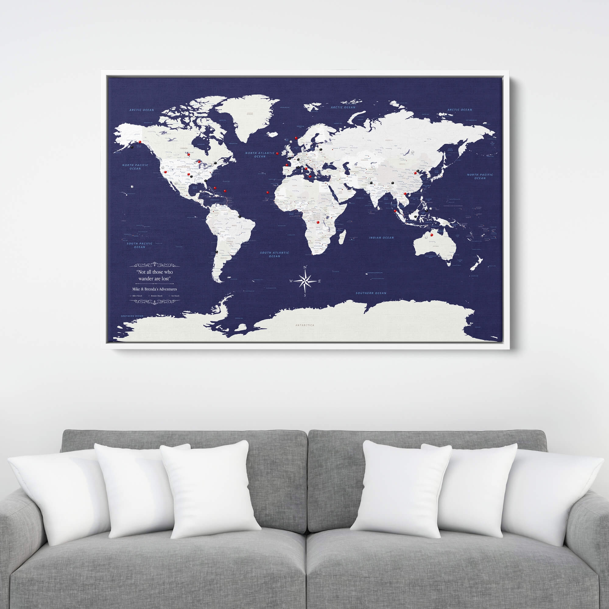 Navy Explorers world travel map canvas with red push pins displayed above gray sofa in living room