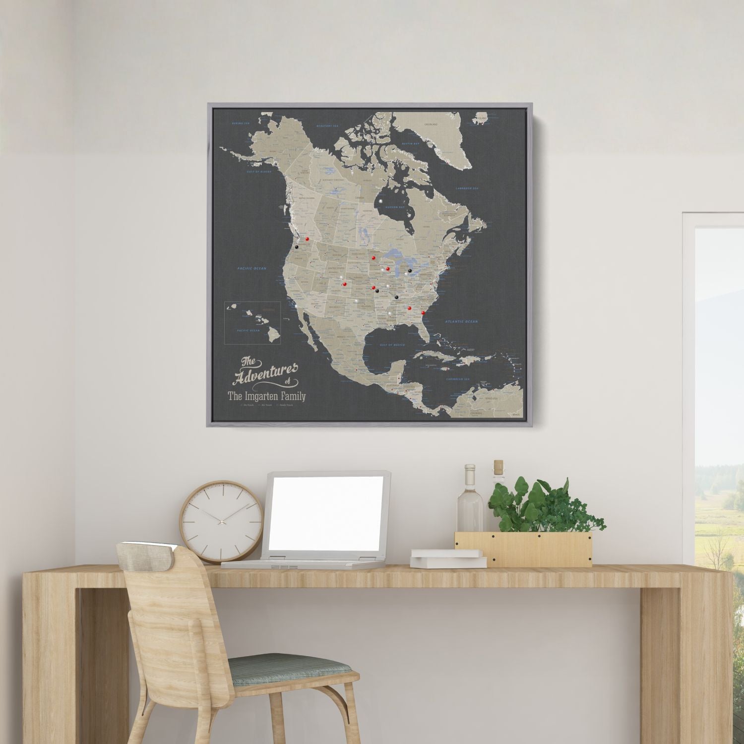 Personalized earth toned North America travel map with push pins in gray frame hung above wooden desk