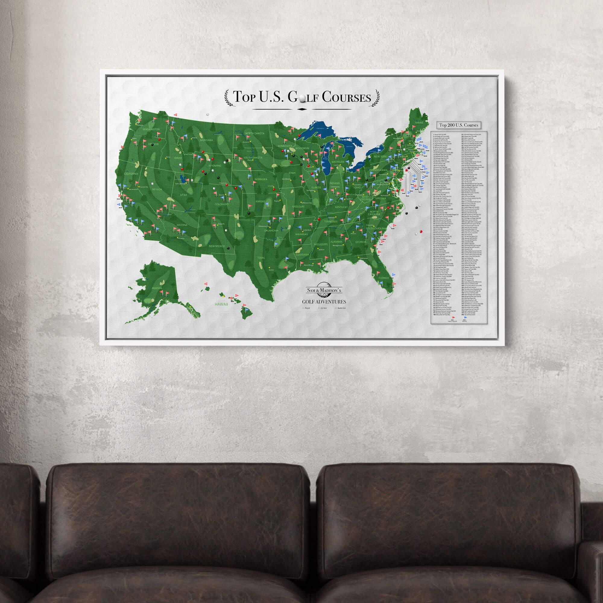 Framed Top US Golf Courses canvas pin map with colored flags hanging above dark leather sofa