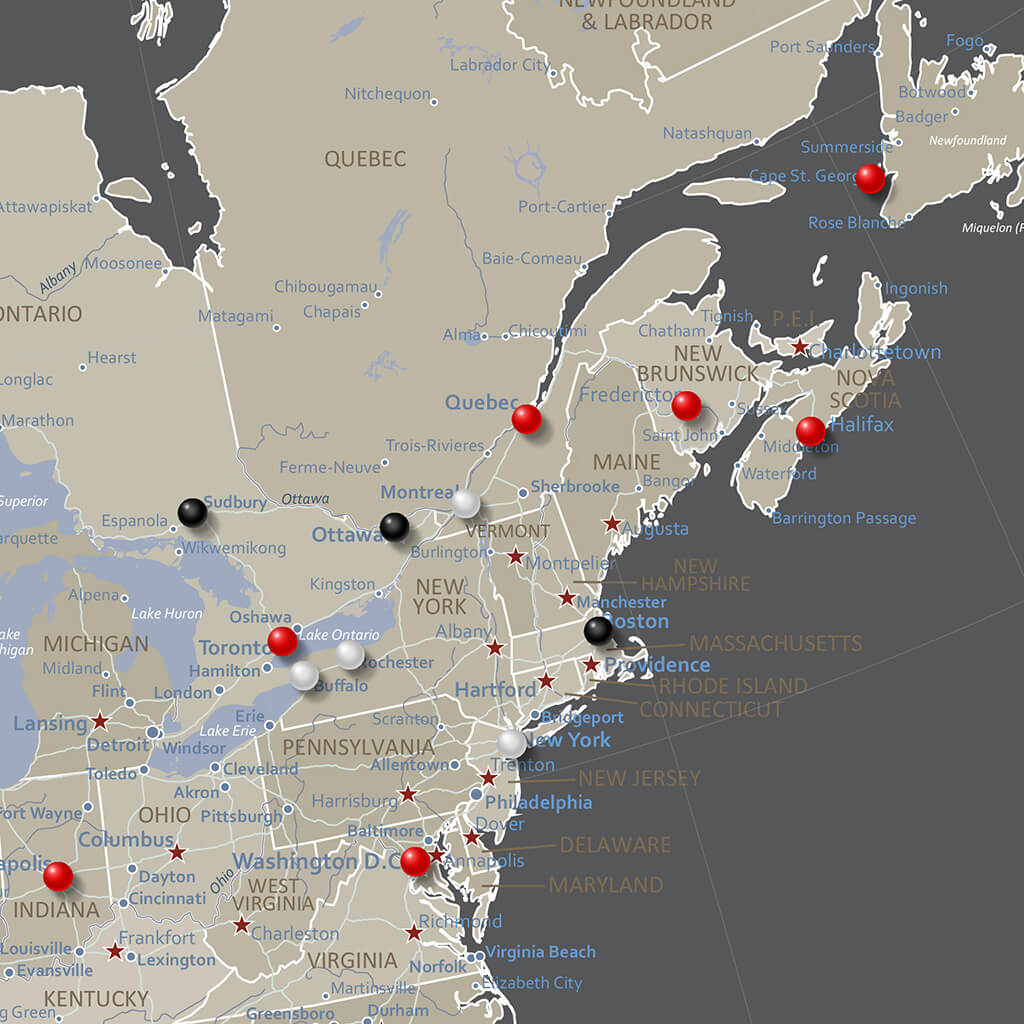 Close-up of earth toned North America travel map with red black and white push pins marking eastern US and Canadian cities