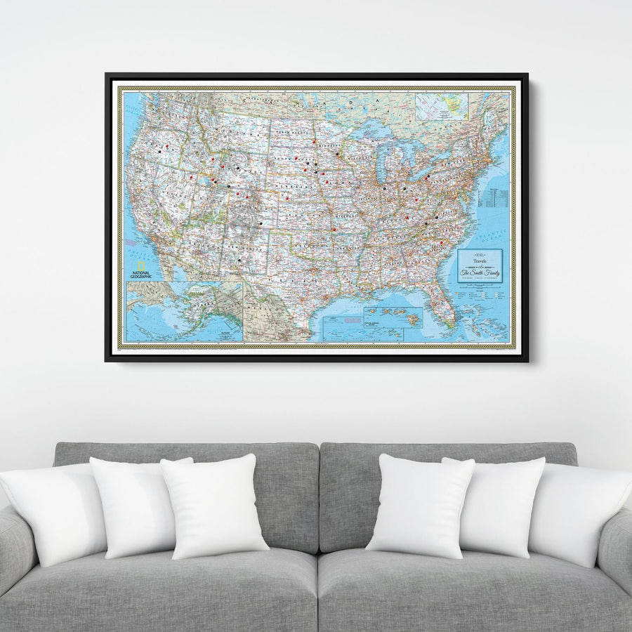 Framed National Geographic Classic USA travel pin map canvas hanging above gray sofa with white pillows