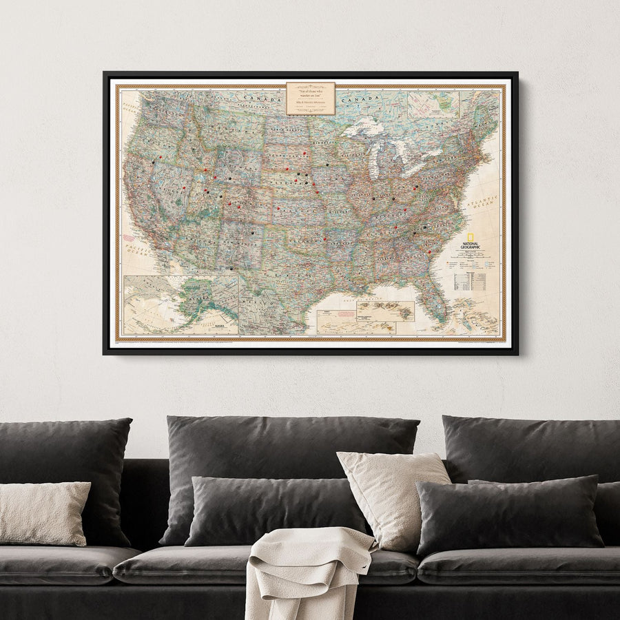 Framed National Geographic Executive USA travel pin map canvas hanging above dark gray sofa in living room