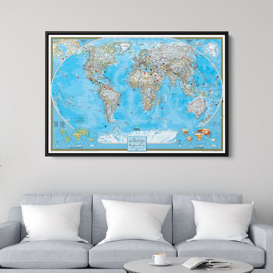 Framed classic National Geographic world travel map with red and black pins hung above gray sofa in modern living room