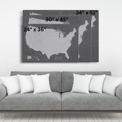 Three size comparison views of grey charcoal USA travel pin map canvas hung above modern sofa