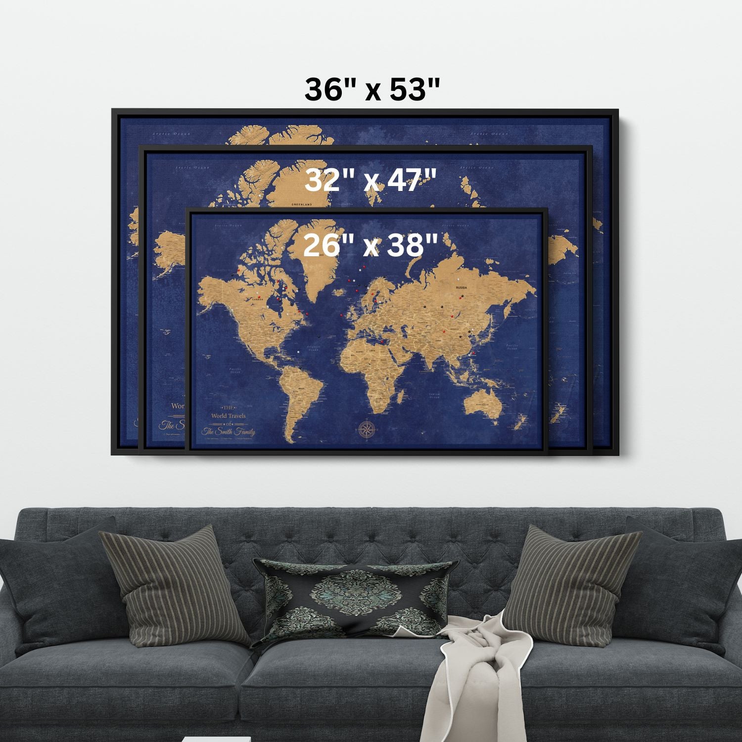 Navy and gold personalized world travel map canvas in three sizes in float frames displayed above gray sofa with push pins