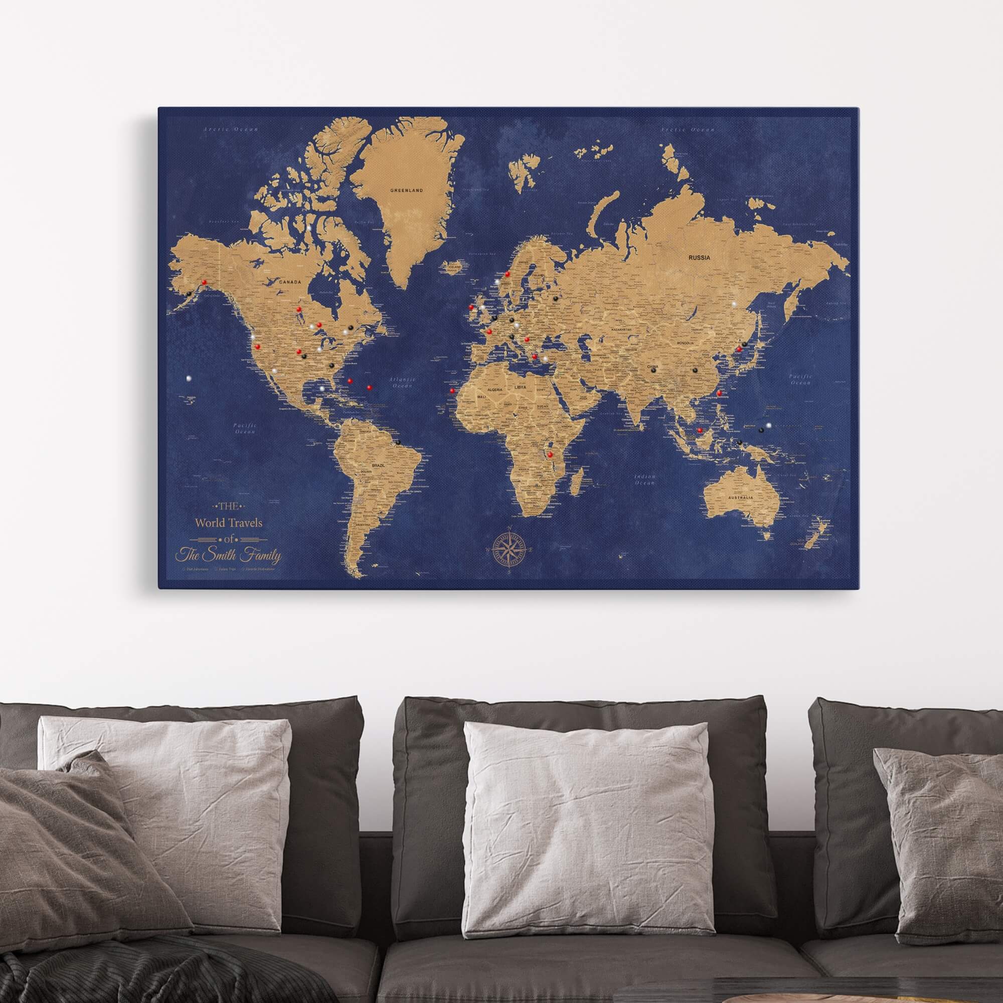 Personalized gold and navy canvas world travel map with push pins displayed above gray sofa