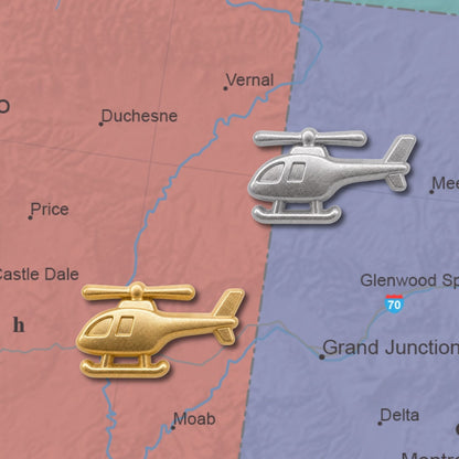 Gold and silver 3D metal helicopter push pins placed on a colorful road map